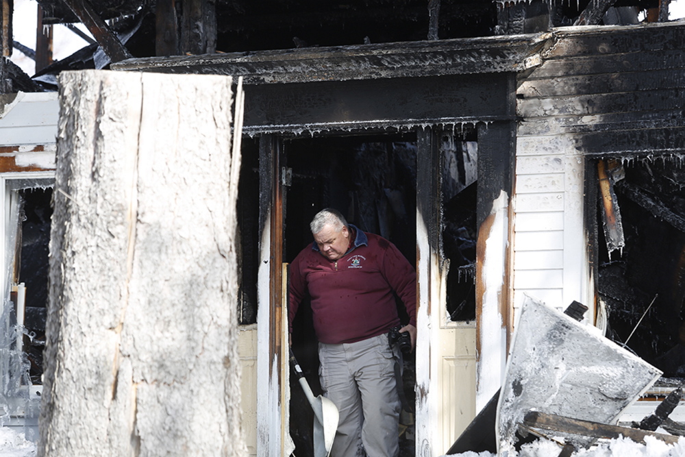 Daniel Young, an investigator with the State Fire Marshal’s Office, leaves the house in Limington where a woman was killed in an early-morning fire Monday.