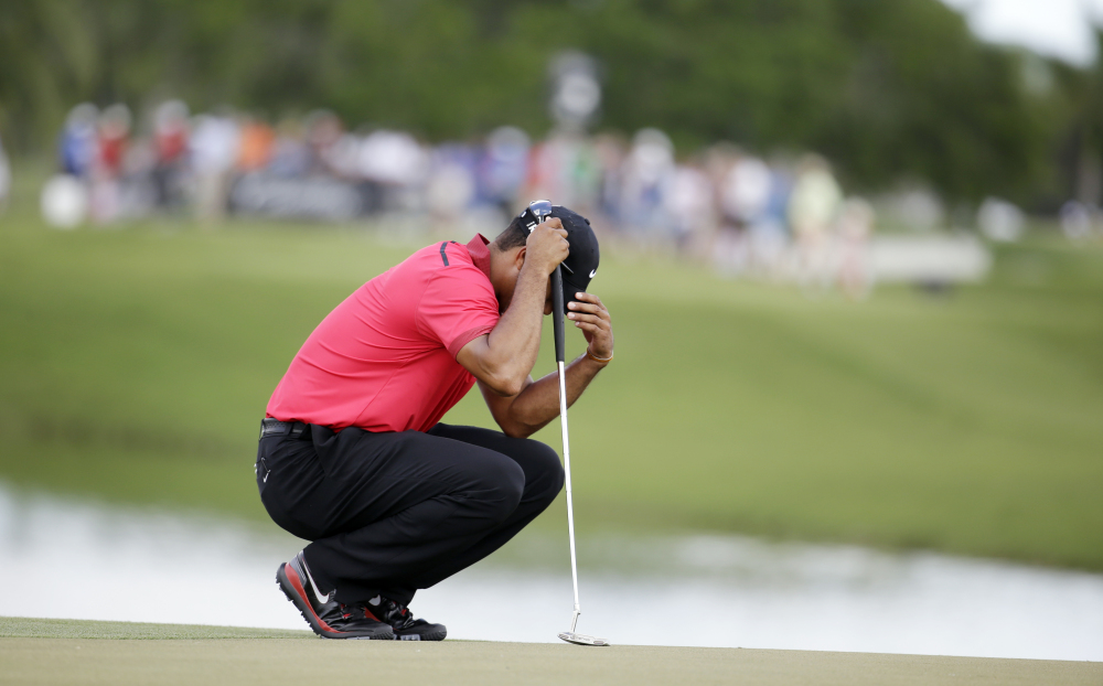 PLAYING THROUGH IT: Tiger Woods bows his head on the fourth green during the final round of the Cadillac Championship on Sunday in Doral, Fla. Woods made bogey on the hole. Woods has been suffering from a lower back injury.