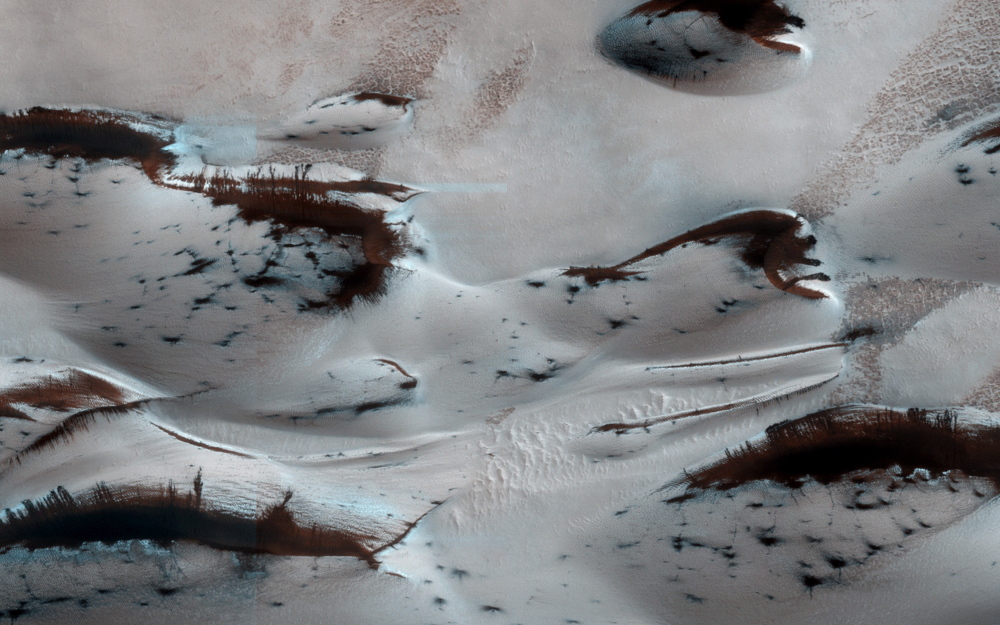 FOURTH ROCK FROM THE SUN: Mars’ northernmost sand dunes begin to emerge from their winter cover of carbon dioxide ice in this image taken by the Mars Reconnaissance Orbiter on Jan. 16. Dark, bare, south-facing slopes are soaking up the warmth of the climbing sun.