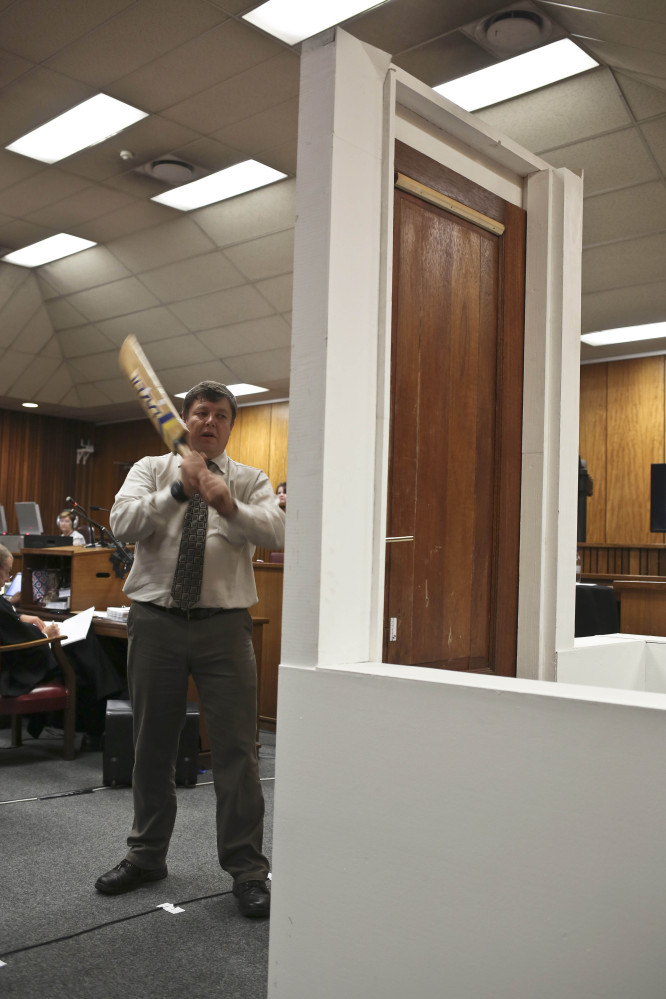 Forensic investigator Johannes Vermeulen, with cricket bat in hand, demonstrates how the toilet door could have been broken down, during the murder trial of Oscar Pistorius.