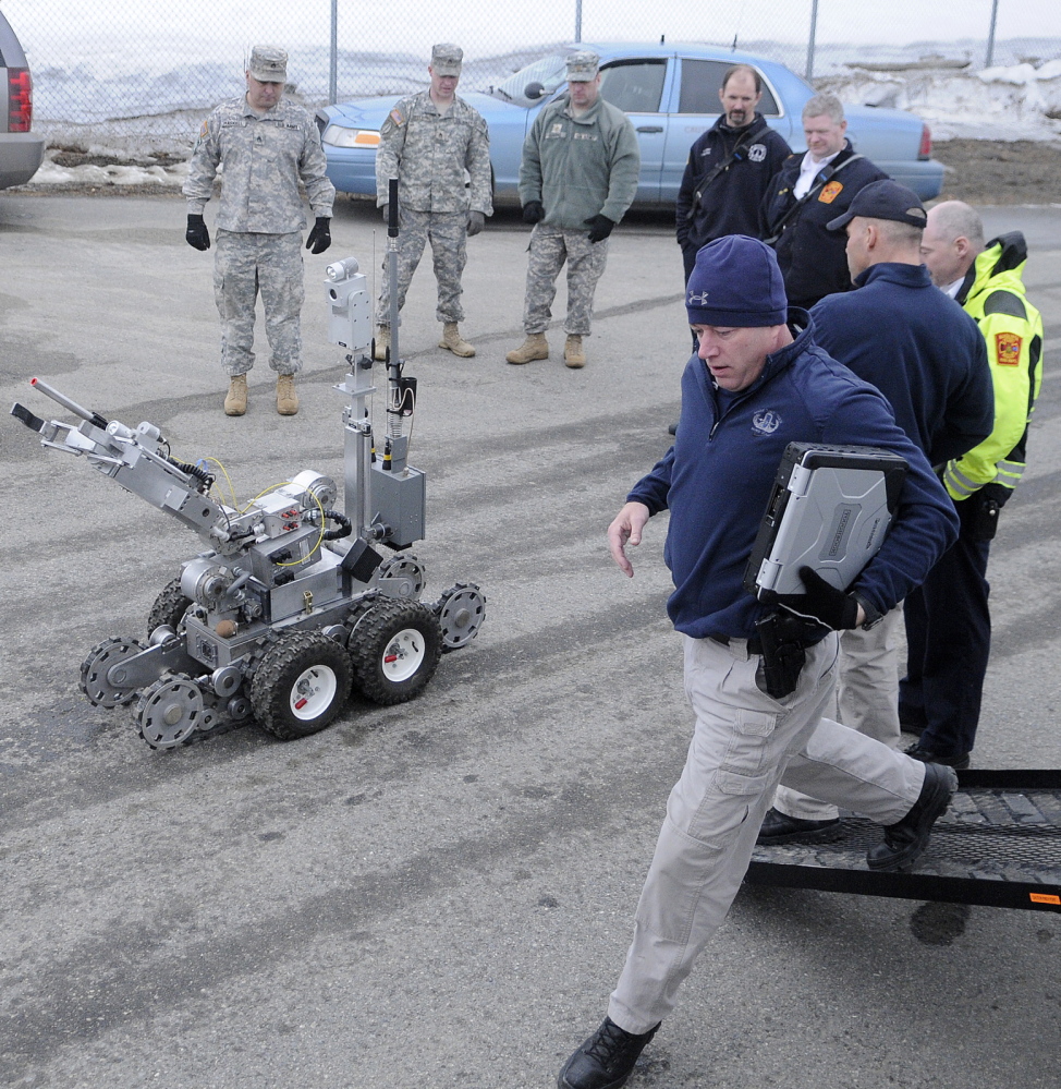 BLAST STOPPER: State Trooper Shawn Whalen, right, runs to operate a robot Wednesday to search for a bomb at Camp Keyes in Augusta during a drill with state, local and federal emergency agencies at the state headquarters of the Army National Guard. The State Police Bombs/Explosives Unit de-activated a “weapon” behind the Augusta State Airport during the training.
