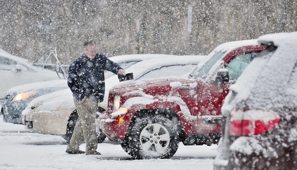 CLEANING UP: Jim Willis cleans off his vehicle after work as snow falls on Wednesday in a parking lot of Water Street in downtown Augusta.