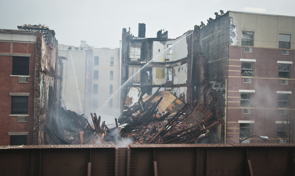 Firefighters spray water on the smoldering debris from an explosion in Harlem Wednesday in New York. A gas leak triggered the explosion that shattered windows a block away, rained debris onto elevated commuter railroad tracks close by, cast a plume of smoke over the skyline and sent people running into the streets.