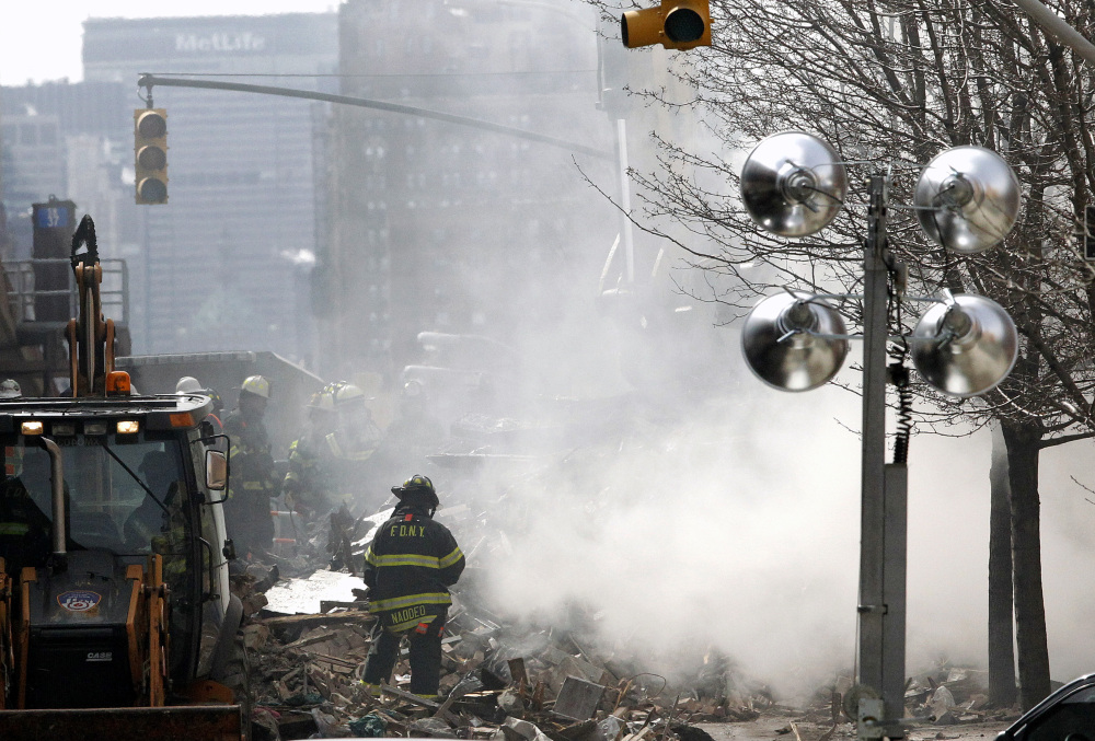 Smoke rises from debris as a firefighter stands near rubble a day after a gas leak-triggered explosion, on Thursday in East Harlem, New York. Rescuers working amid gusty winds, cold temperatures and billowing smoke continued to search for five people still unaccounted for Thursday.