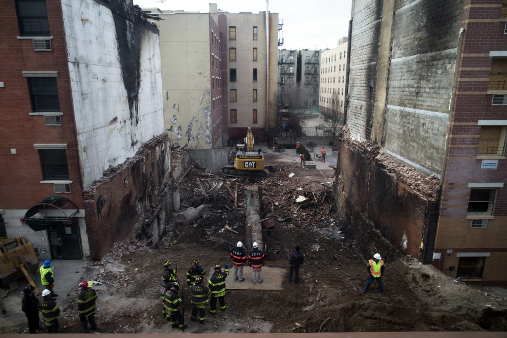 Workers stand beside the recently cleared basement of the two buildings leveled by an explosion on Wednesday in the East Harlem neighborhood of New York, Sunday.
