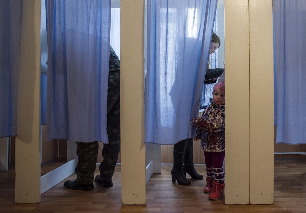 A young girl peeks out of a voting booth at a polling station during the Crimean referendum in Orlinoe, near Sevastopol, Ukraine, on Sunday.