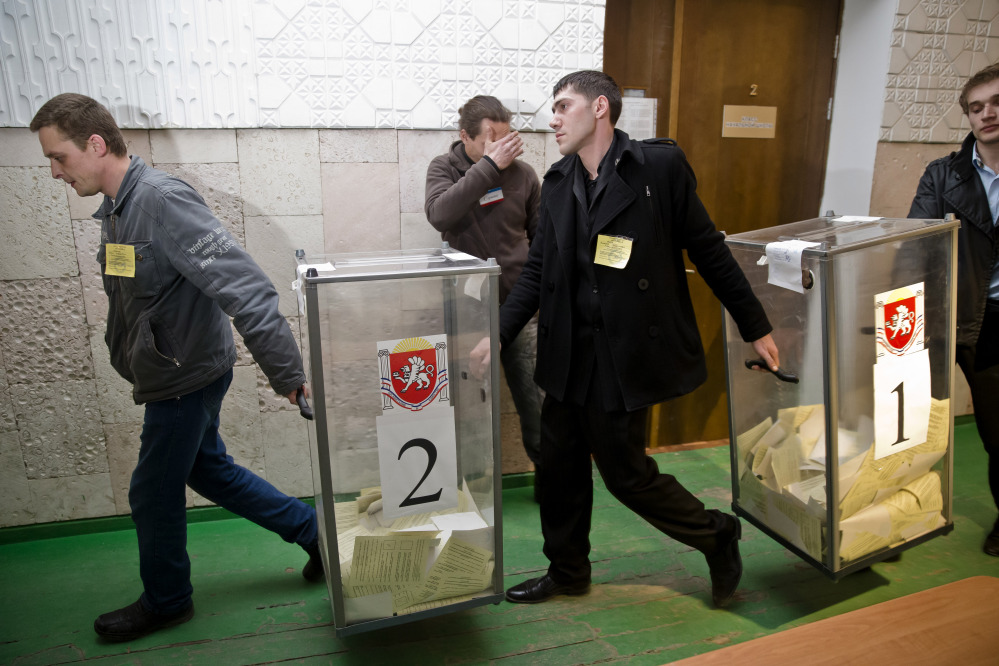 Referendum officials carry ballot boxes at a polling station after voting ended in Simferopol, Ukraine, Sunday, March 16, 2014. Polls have closed in Crimea’s contentious referendum on seceding from Ukraine and seeking annexation by Russia.