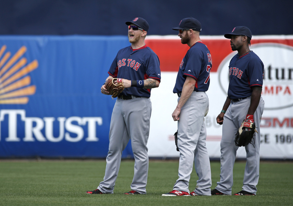 Boston Red Sox left fielder Mike Carp, left, calls to an umpire explaining that a swarm of bees have taken over left, field in the bottom of the third inning as Red Sox right fielder Corey Brown, center, and center fielder Jackie Bradley Jr. watch during a spring exhibition baseball game against the New York Yankees in Tampa, Fla., Tuesday, March 18, 2014. The game was delayed seven minutes as groundskeepers eradicated the swarm with insecticide.
