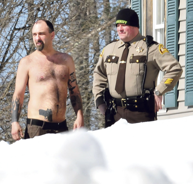 Staff photo by David LeamingCLOSE CALL: Norridgewock resident Michael Smith stands beside a Somerset County sheriff’s deputy Tuesday morning. The tattoo of a pistol on his stomach was mistaken for a real firearm by employees of Lucas Tree Experts after, according to Smith, workers woke him up while they were cutting wood for Central Maine Power Co. The workers called police.