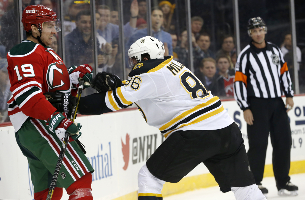 New Jersey Devils center Travis Zajac (19) is pushed by Boston Bruins defenseman Kevan Miller (86) during the second period of an NHL hockey game, Tuesday, March 18, 2014, in Newark, N.J.
