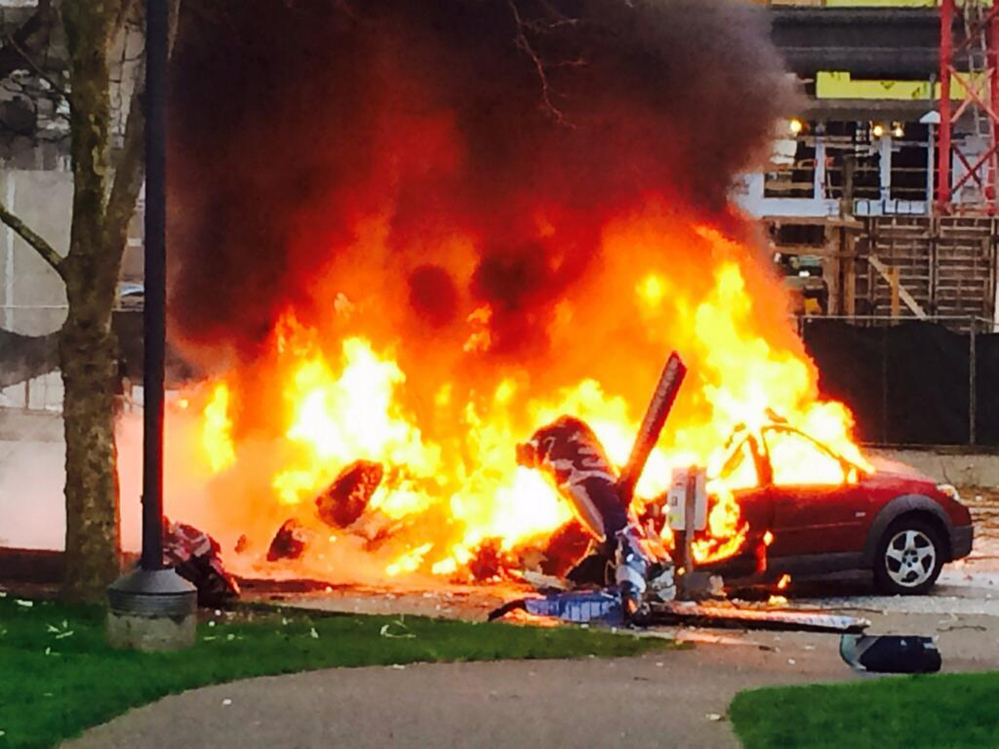 In this photo provided by KOMO-TV, a car burns at the scene of a helicopter crash outside the KOMO-TV studios near the Space Needle in Seattle on Tuesday.
