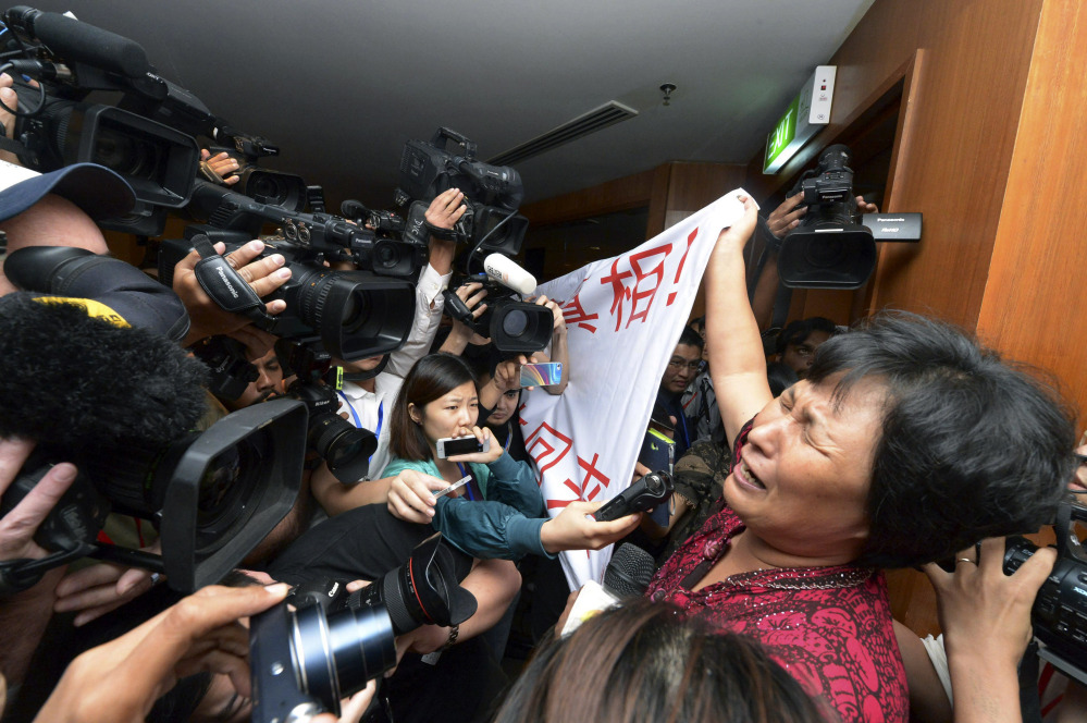 A Chinese relative of passengers aboard a missing Malaysia Airlines plane cries as she holds a banner in front of journalists reading ‘We are against the Malaysian government for hiding the truth and delaying the rescue. Release our families unconditionally!” at a hotel in Sepang, Malaysia, Wednesday, March 19, 2014. Malaysian authorities examined new radar data from Thailand that could potentially give clues on how to retrace the course of the Malaysia Airlines plane that vanished early March 8 with 239 people aboard en route from Kuala Lumpur to Beijing. Twenty-six countries are looking for the aircraft as relatives anxiously await news.