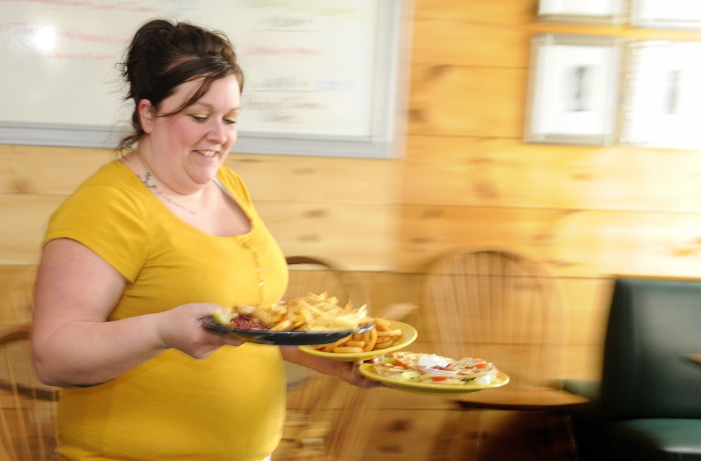 BUSINESS GOOD: Waitress Jessica Grant carries lunch out to a table for customers on Friday at Lisa’s Restaurant and Catering on Bangor Street in Augusta.