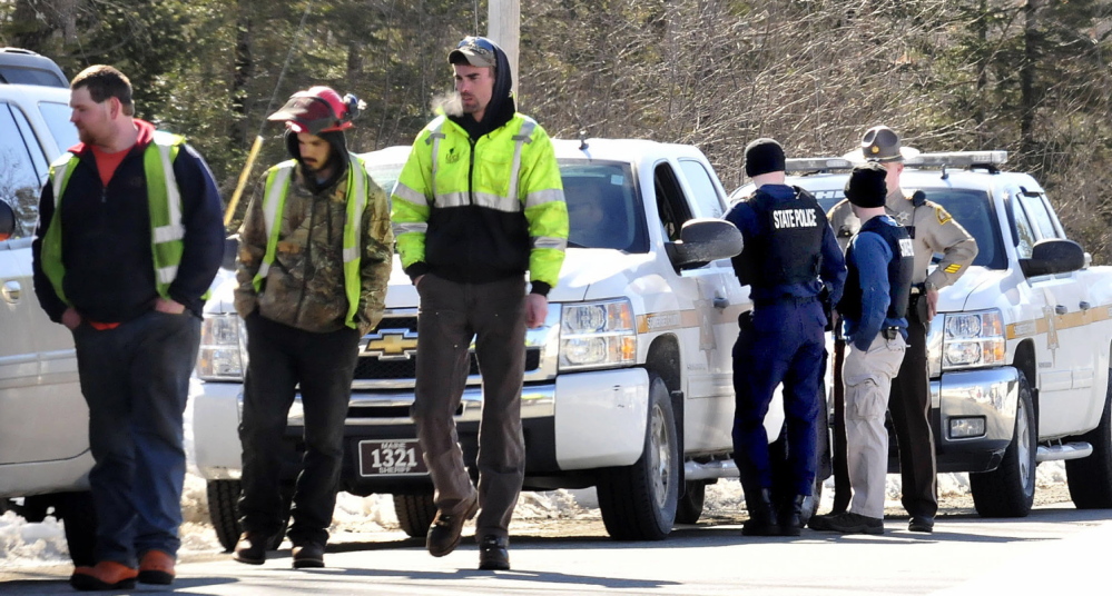 POLICE SUMMONED: Three employees of Lucas Tree Experts walk away after talking to state troopers and Somerset County sheriff deputies who were discussing how to approach nearby resident Michael Smith on Tuesday. Smith had told the workers to leave his property and not cut wood under power lines and the workers mistook a tattoo of a gun on Smith’s stomach for a real one and called