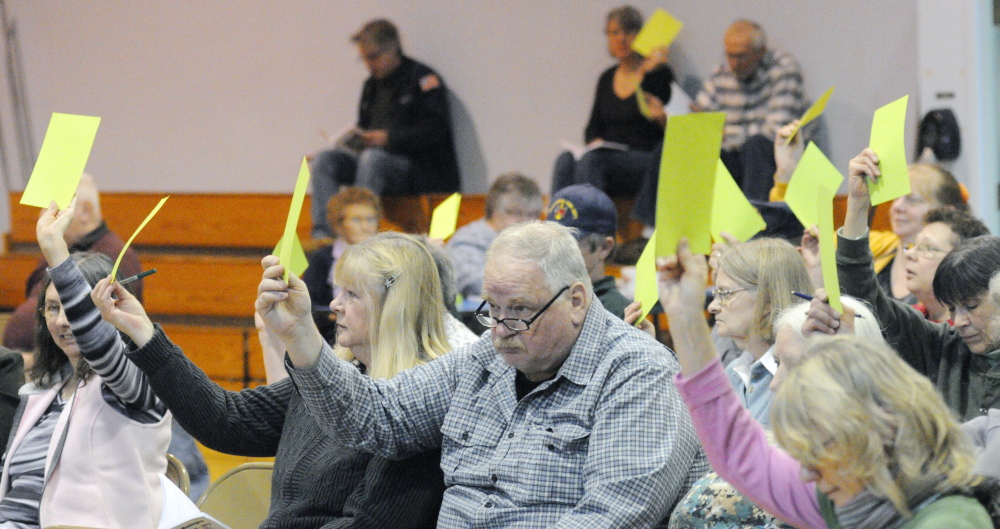 Voting: Residents hold up green cards to cast votes during Washington’s Town Meeting on Saturday in Prescott Memorial School in Washington.