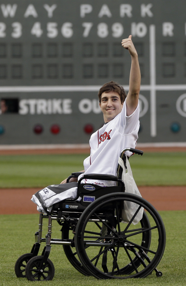 Boston Marathon bombing survivor Jeff Bauman acknowledges cheering fans before throwing out a ceremonial first pitch at Fenway Park on May 28, 2013, before the Red Sox played the Philadelphia Phillies.