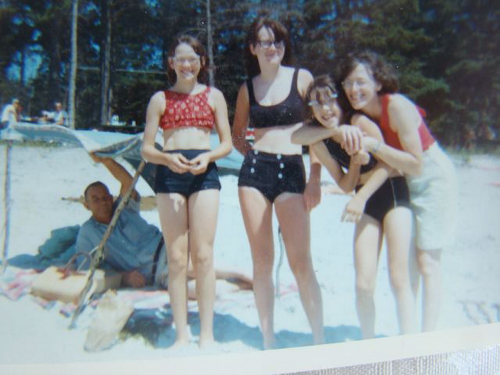 Eyeglass family: Amy Calder, second from right, with her mother, Frances Calder, hugging her. Her sister Jane is at far left, and sister Katherine in the middle. Amy’s father, Edwin Calder, is under the umbrella. The photo was taken at Pemaquid Beach in the 1960s.