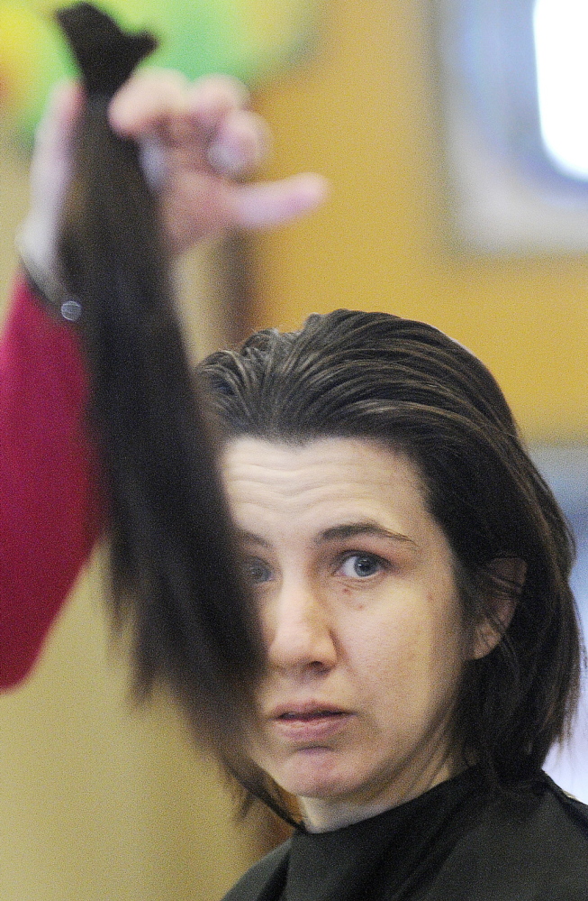 GIVING BACK: Leah Estey of Augusta looks at the hair she donated Monday to Locks of Love, a charity that gives hair to children, during an event at the University of Maine at Augusta. Students from Capilo Institute of Augusta donated their services to cut the hair.