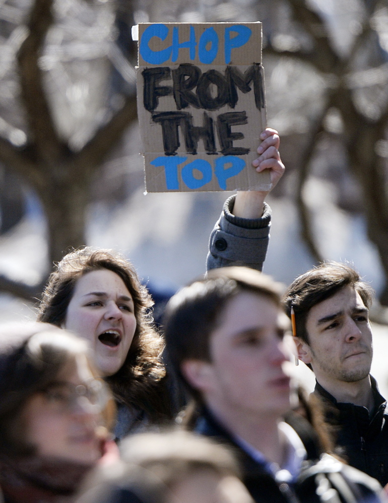 Rhiannon Vonder Haar, back left, a sophomore at the University of Southern Maine, shouts while holding a sign as students and faculty protest program cuts and faculty layoffs at USM on Monday. The cuts are intended to address the school’s $14 million budget gap for the fiscal year that begins July 1.