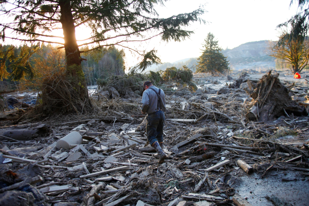 Steve Skaglund walks across the rubble on the east side of the fatal mudslide near Oso, Wash., on Sunday.
