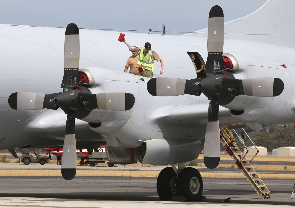 Ground crew members work on a Royal Australian Air Force AP-3C Orion on the tarmac in Perth, Australia, on Tuesday. All search and rescue flights for the missing Malaysia Airlines flight MH370 were canceled for Tuesday because of bad weather in the search area.