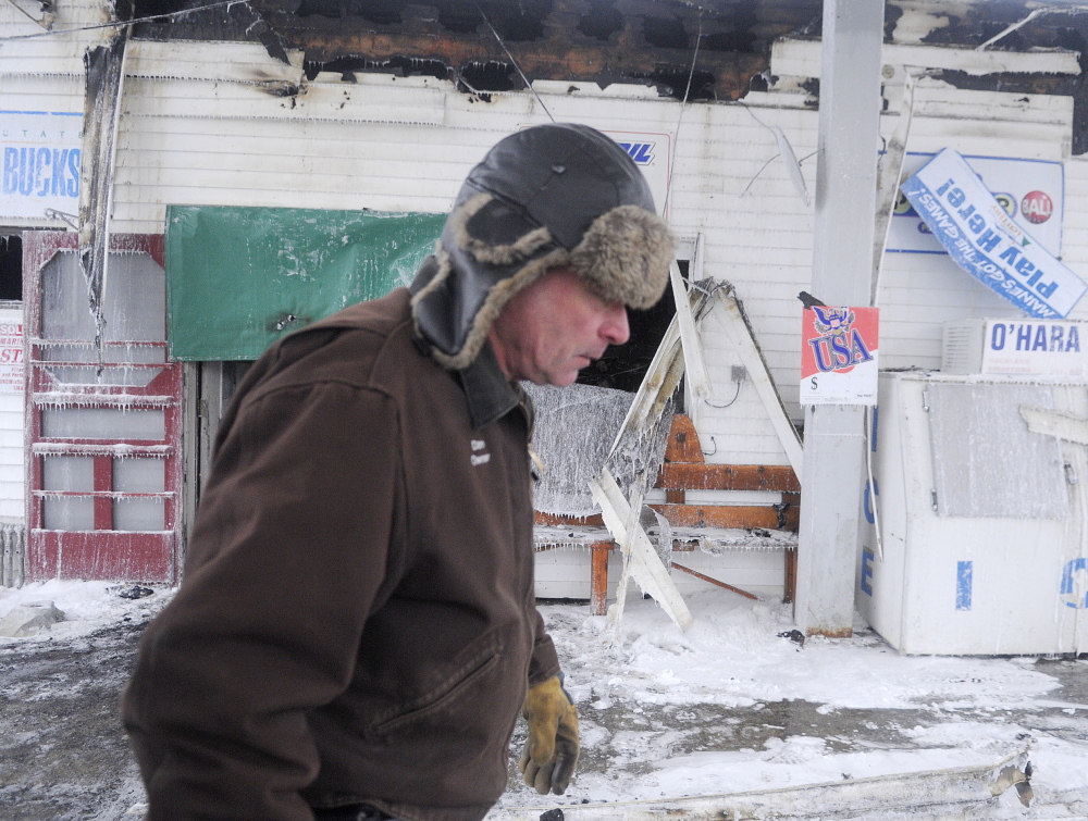 AFTERMATH: Webb’s Store owner Dan Kilmer walks past the burned business Wednesday morning after an early morning fire. Kilmer said his security firm called him at 3 am to report an alarm and when he arrived minutes later, the building was engulfed in smoke.