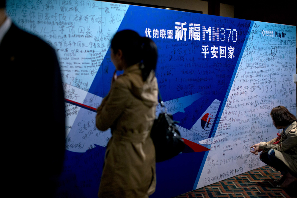 Journalists read words from board covered by written wishes from relatives during a briefing meeting given by Malaysian officials at a hotel in Beijing, China, Wednesday, March 26, 2014. Some of the wishes read, “Dear husband, you must stay strong, I am waiting for you. My dear, please be back soon.” The search of the missing plan resumed Wednesday after fierce winds and high waves forced crews to take a break Tuesday. A total of 12 planes and five ships from the United States, China, Japan, South Korea, Australia and New Zealand were participating in the search, hoping to find even a single piece of the jet that could offer tangible evidence of a crash and provide clues to find the rest of the wreckage.