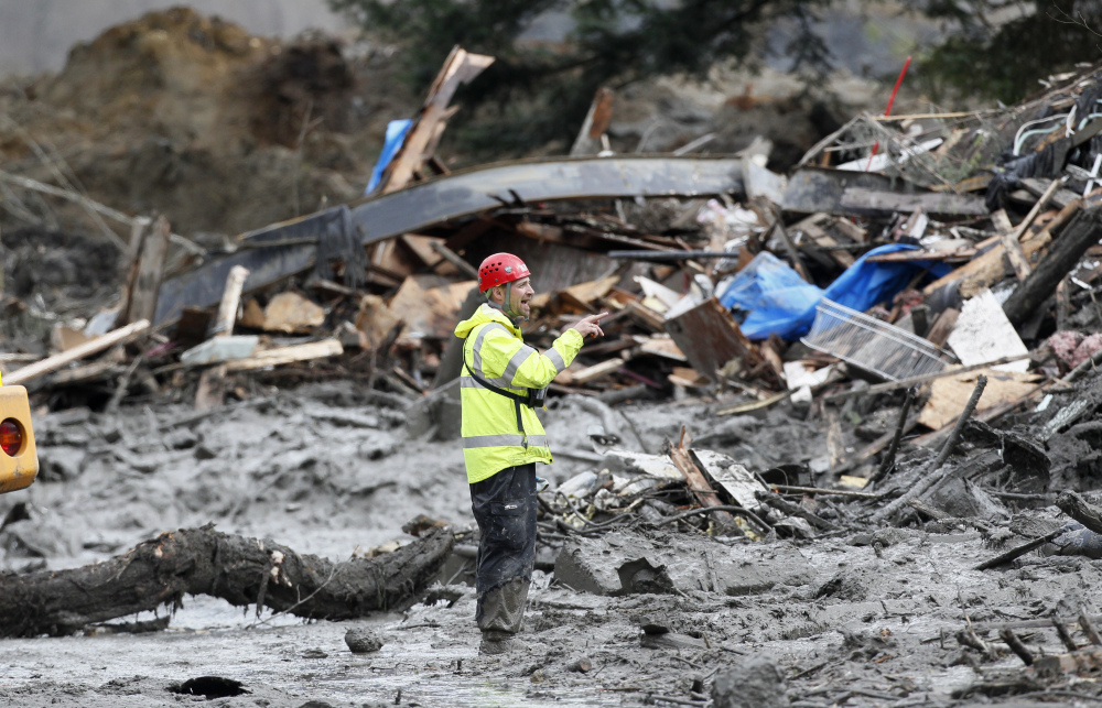A searcher stands among debris at the scene of the deadly mudslide in Oso, Wash., on Wednesday. The debris field is about a square mile and, in places, 30 to 40 feet deep.