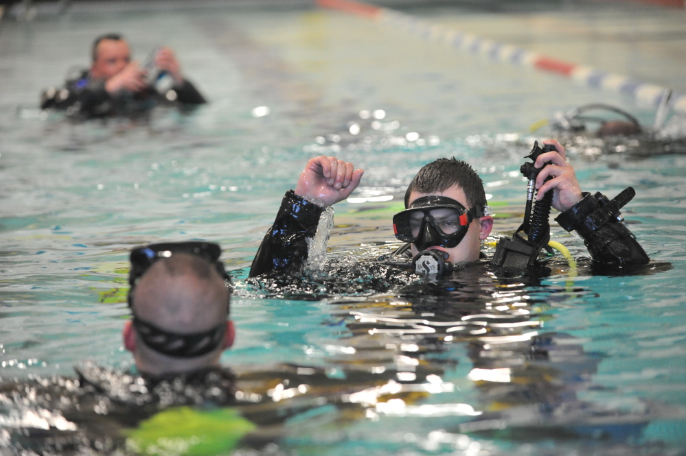 Masked men: Dive team members cluster in the pool at the Alfond Youth Center in Waterville on Tuesday.