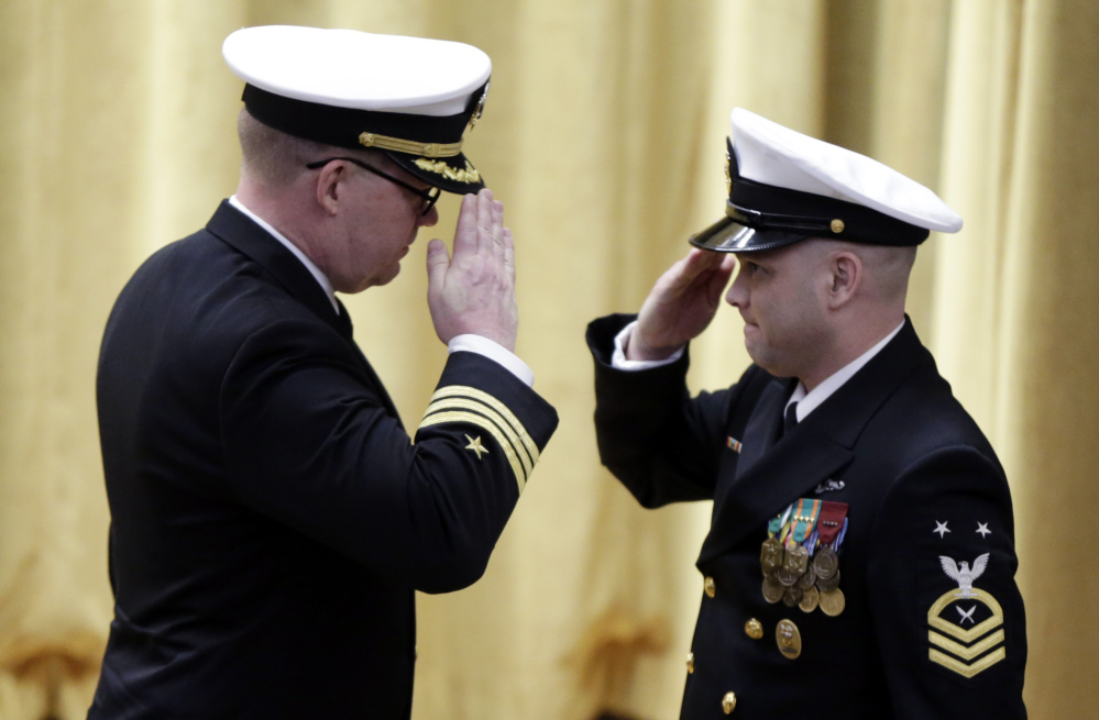 Cmdr. Rolf Spelker, left, salutes a sailor at the decommissioning ceremony for the fire-damaged USS Miami nuclear submarine at the Portsmouth Naval Shipyard on Friday in Kittery.