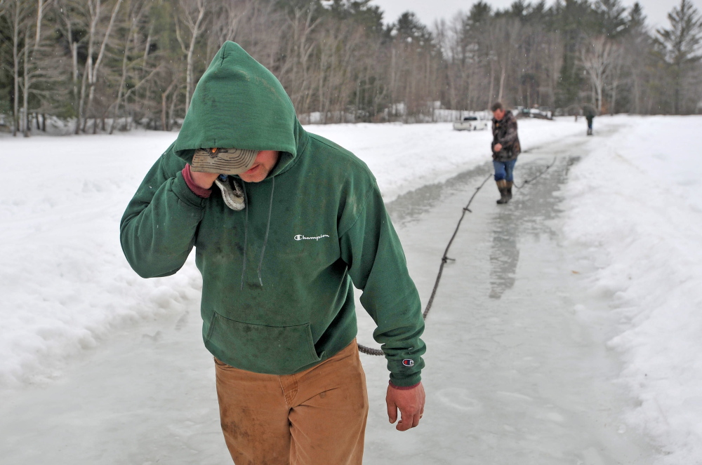 SOFT ICE: Steve Richardson, foreground, and Dave Richardson lay out nearly a quarter-mile of ropes and chains from Roger Hodgdon’s flatbed wrecker on Friday in a attempt to haul a stuck pickup truck from the broken ice at Lake George in Canaan. Richardson’s truck broke through about 2 feet of ice, coming to rest on another layer of ice and lake water as they were trying to clear their ice fishing shack from the lake ahead of an April 1 deadline.