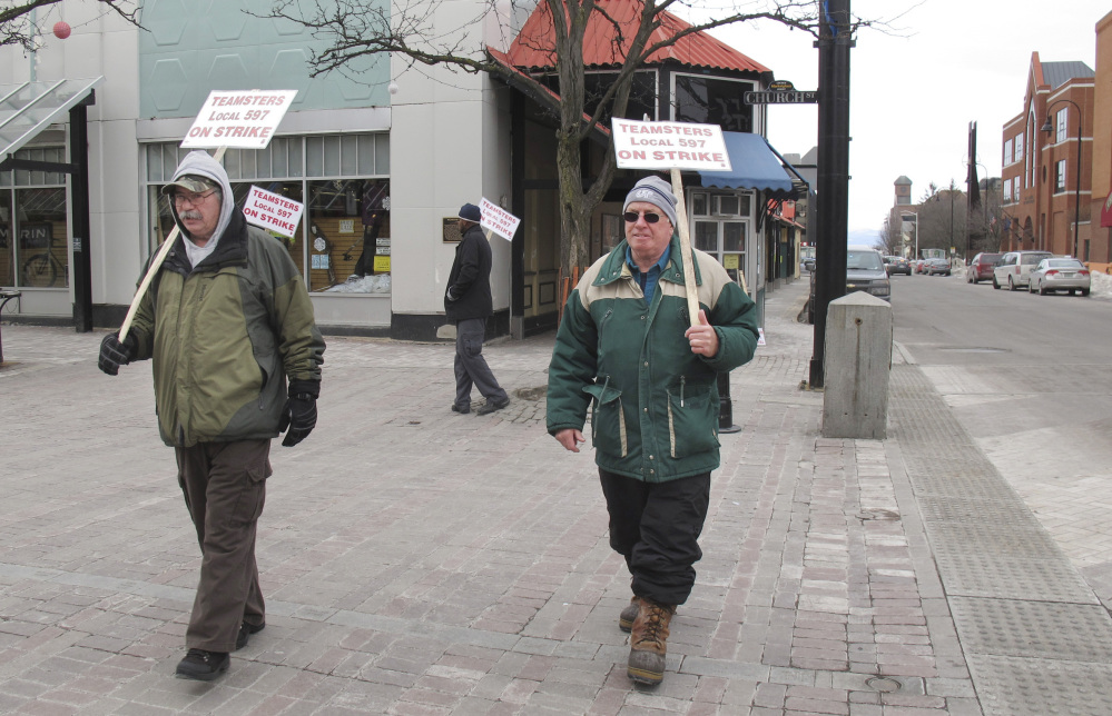 Striking bus drivers Rick LaFerriere, left, and Derek Lorrain walk a picket line Wednesday in Burlington, Vt. The strike continued into a second week, leaving thousands of people scrambling to find ways to get to work, school and appointments.