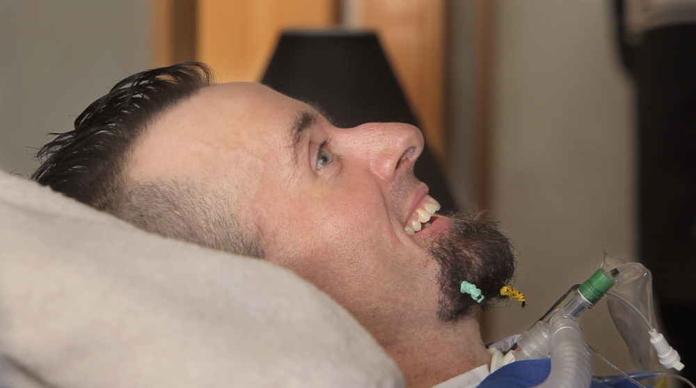 Nick Stanley smiles as he listens to the rapper Spose perform. Stanley has been confined to bed for two years because of complications from adult onset spinal muscular atrophy.