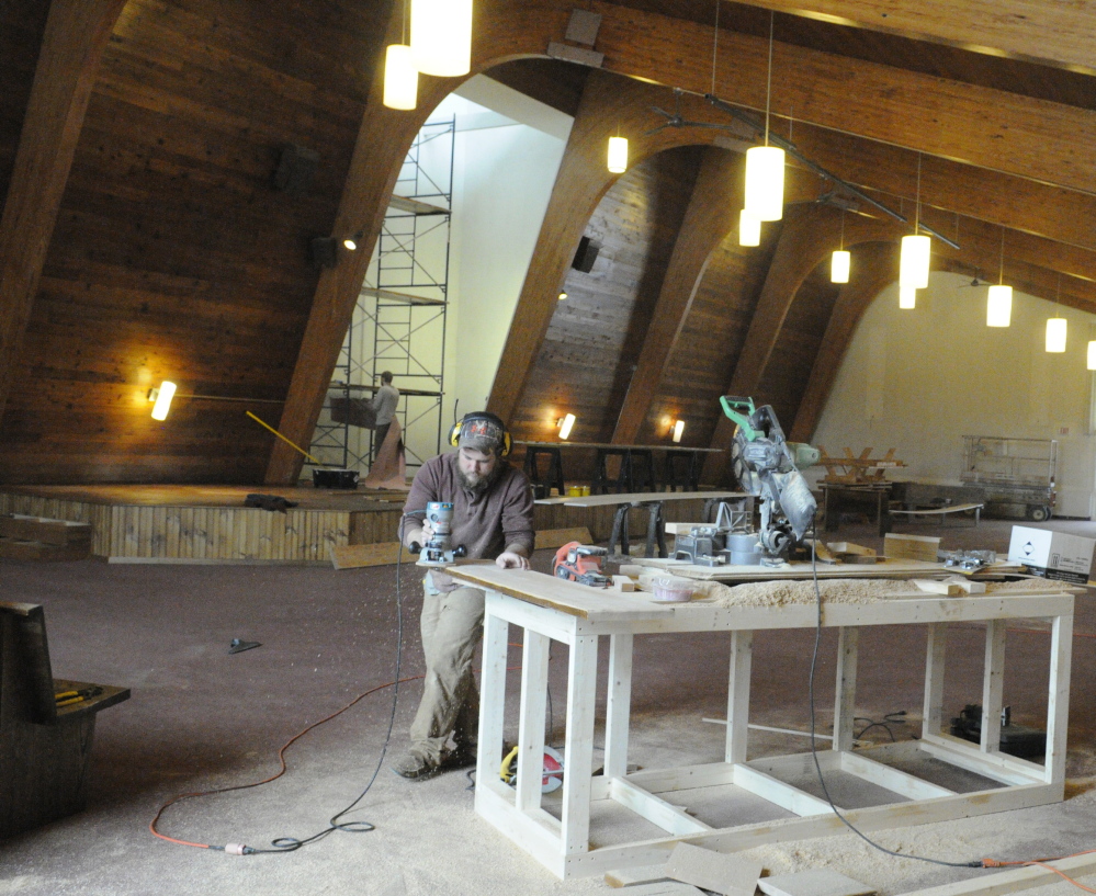 From sitting to standing: Jon Avery runs a router around a board from an old pew that he is turning into a stair tread March 22 at the new Kennebec Community Church in Augusta. Avery, a pastoral intern, said the stage behind him had been built from the former Catholic church’s pews.