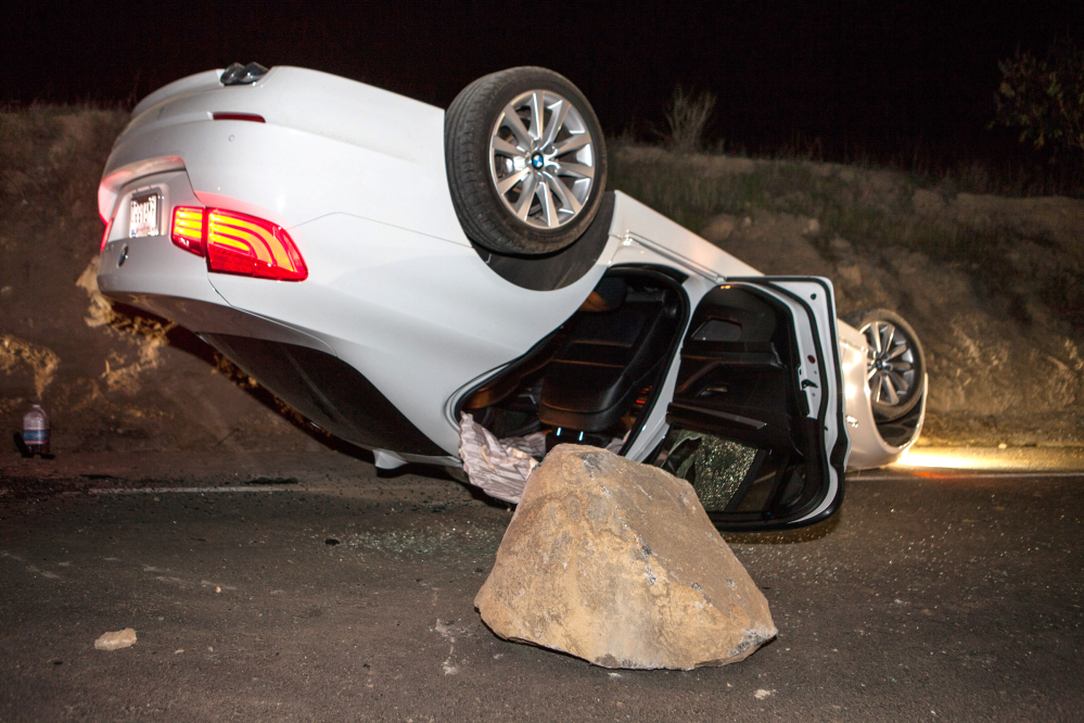 A car overturned on a highway in the Carbon Canyon area of Brea, Calif., Friday night after hitting a rock slide caused by an earthquake. The people inside the car sustained minor injuries.
