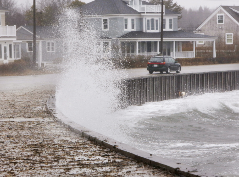 KENNEBUNK, ME - MARCH 30 A car drives along Beach Avenue in Kennebunk on Sunday, March 30, 2014 as a wave hits a seawall, spalshing water on to the sidewalk. A combination of an astronmical high tide and strong winds caused minor coastal flooding along areas of the southern Maine coast on Sunday. (Photo by Gregory Rec/Portland Press Herald)