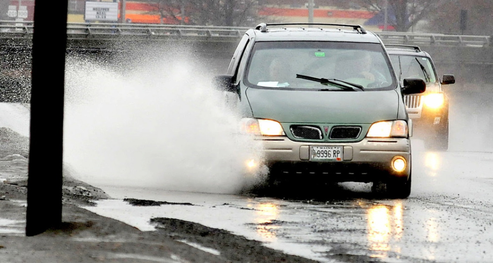 Staff photo by David Leaming SPLASH: Motorists drive through water puddles made from steady rain on Sunday, March 30, 2014, in Waterville. Parts of Franklin and Somerset counties were expected to get both rain and snow later in the day.