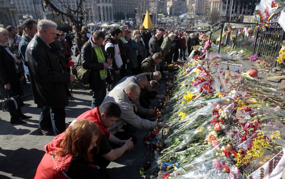 People lay flowers and lit candles at one of the barricades during a mourning rally in memory of those killed during mass protests in Kiev in Kiev’s Independence Square on Sunday.