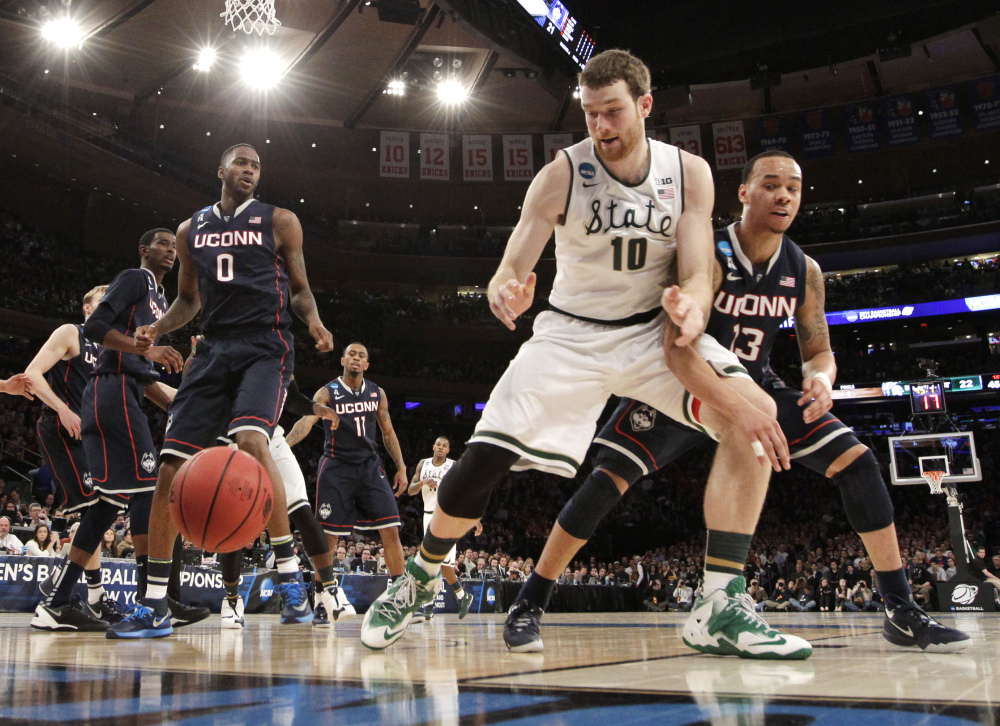 Michigan State’s Matt Costello, center, looks for the ball while covered by Connecticut’s Shabazz Napier, right, in the first half of a regional final at the NCAA college basketball tournament on Sunday.