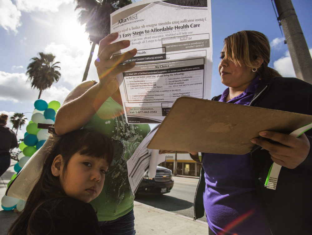 Staffer Jessica Figueroa, right, assists Maria Banajas, 40, and her daughter Camila, 3, during a health care enrollment event at AltaMed Health Insurance Resource Center on Monday in Los Angeles. Monday is the open enrollment deadline for signing up for insurance under the federal Affordable Care Act.
