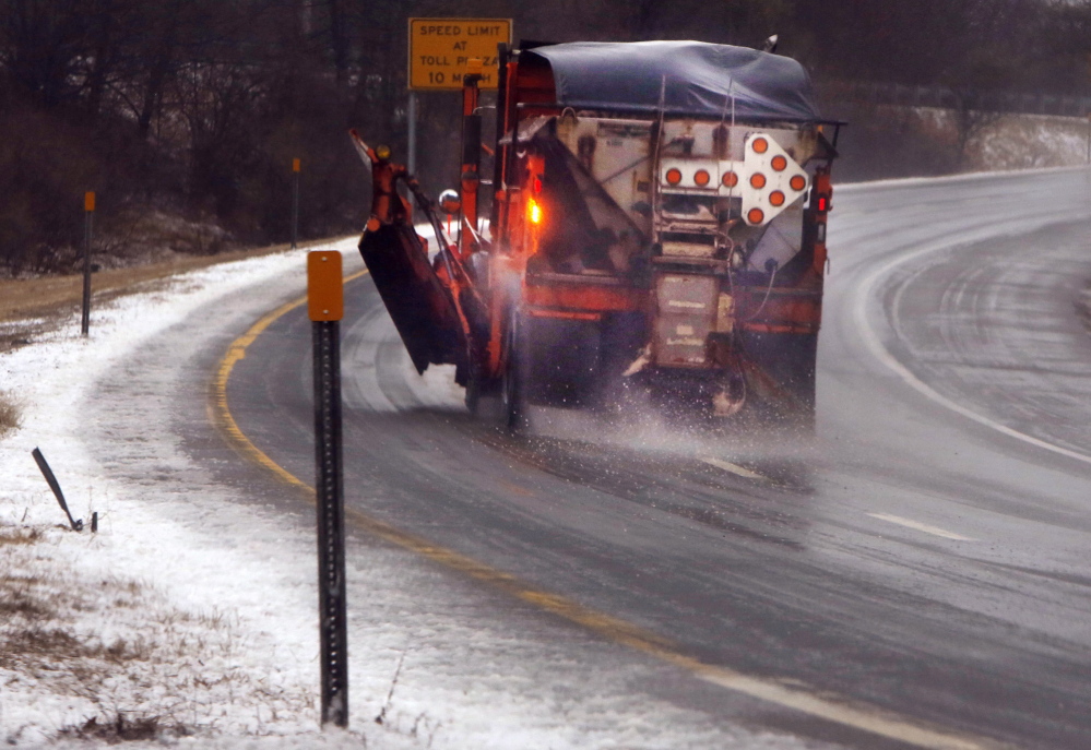 A snowplow spreads sand on the ramp from the Maine Turnpike to I-295 in Scarborough. A wintry mix caused a spate of accidents on roads throughout southern Maine on Monday morning.