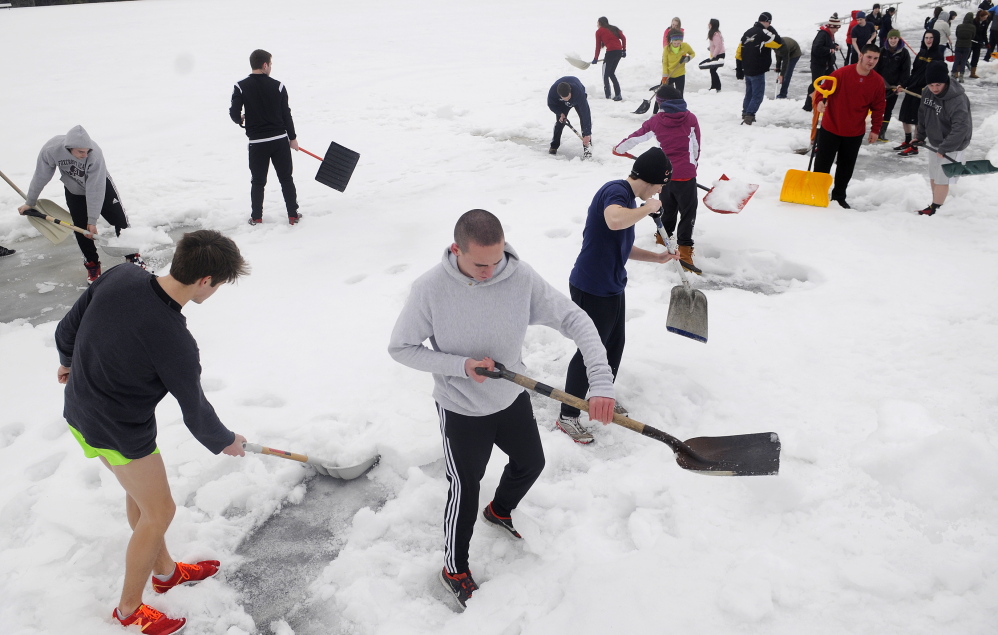 Staff photo by Andy Molloy SHOVEL READY: Hall-Dale High School track team members began practice Monday, the first day of spring sports, by clearing the track. The forty athletes removed several inches of snow from six lanes of the track for about 200 meters.