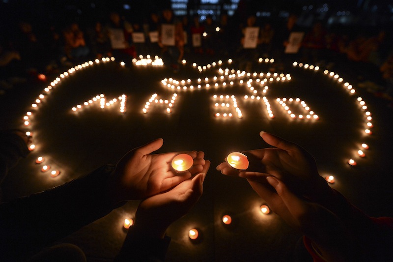 In this Thursday March 13, 2014 photo, university students hold a candlelight vigil for passengers on the missing Malaysia Airlines Flight MH370 in Yangzhou, in eastern China's Jiangsu province. China on Friday urged Malaysia's government to release any information it has regarding the missing Malaysia Airlines jetliner to help narrow the search area.
