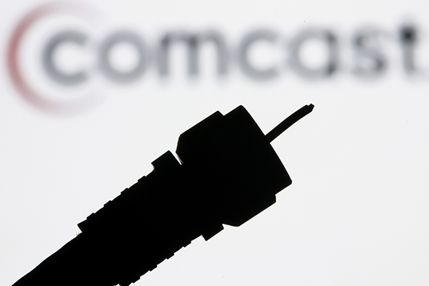 In this July 30, 2008 file photo illustration, a silhouetted coaxial cable is photographed with the Comcast Corp. logo in the background in Philadelphia.