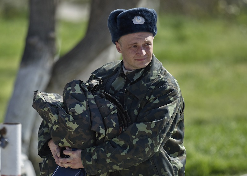 A Ukrainian airman carries belongings as he leaves the Belbek air base, outside Sevastopol, Crimea, Friday, March 21, 2014. The base commander Col. Yuliy Mamchur said he was asked by the Russian military to turn over the base but is unwilling to do so until he receives orders from the Ukrainian defense ministry.