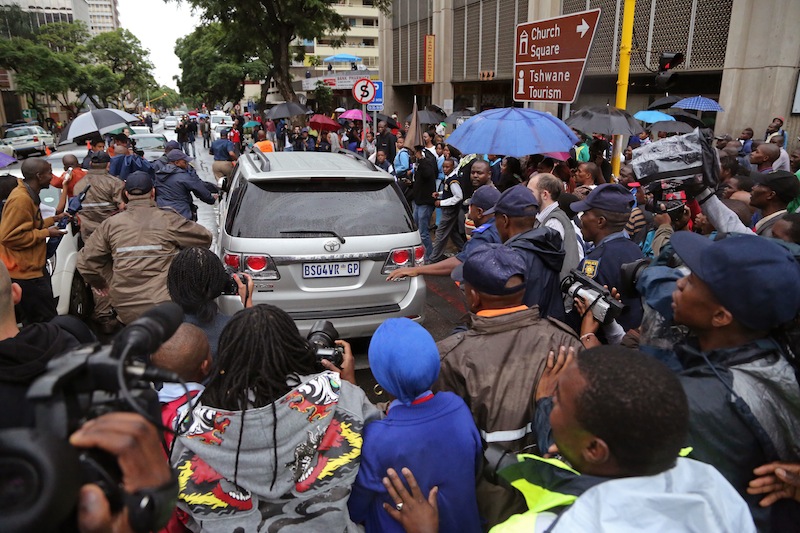 People run after the car that is transporting Oscar Pistorius from the high court after the first day of his trial in Pretoria, South Africa, Monday, March 3, 2014. Pistorius is charged with murder with premeditation in the shooting death of girlfriend Reeva Steenkamp in the pre-dawn hours of Valentine's Day 2013.