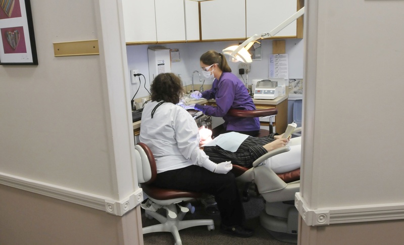 In this November 2012 file photo, Dr. Denise Theriault and hygienist Stephanie Fortier work on a patient at Dustan Dental Center. A new type of dental provider – “mid-level dental therapist” – is likely on its way to becoming a reality in Maine.