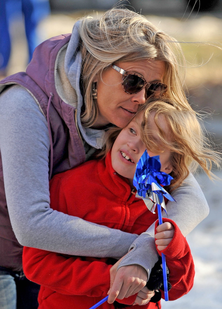 Staff photo by Michael G. Seamans Morrigan Knox-McLeod cuddles with her daughter Ava Doody-McLeod, 7, during the child abuse awareness rally at Castonguay Square in Waterville on Wednesday.