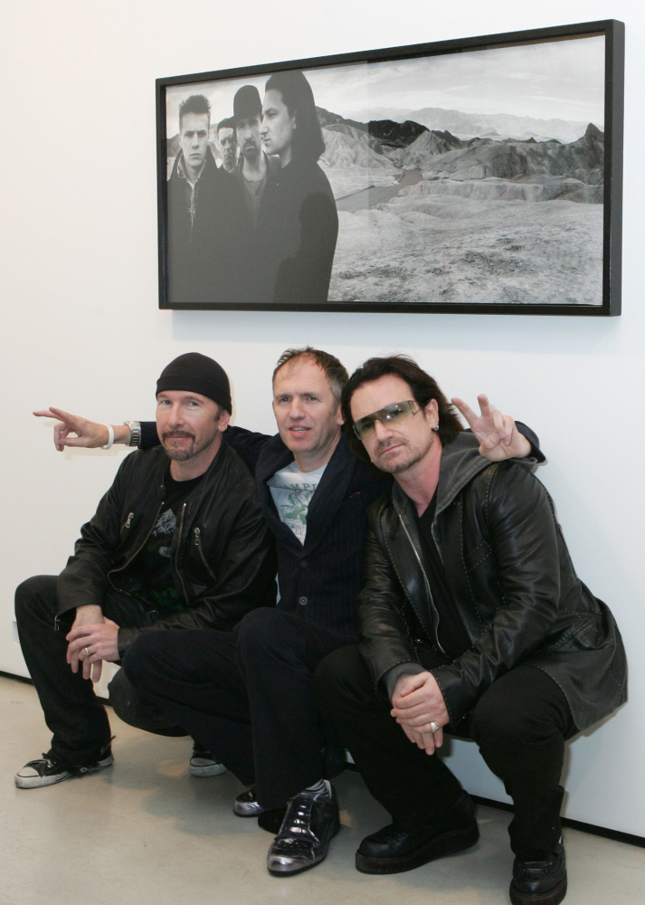 U2’s Bono, right, and guitarist The Edge, left, pose with photographer Anton Corbijn in New York, under a portrait of the band from the Joshua Tree album cover, in gthis 2005 photo.