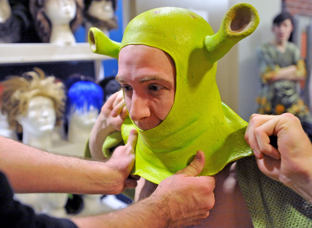 Staff photo by Michael G. Seamans Dan Kennedy gets help with his Shrek costume from costume and hair designer, Kurt Alger, as the cast prepares for the first dress rehearsal of Shrek the Musical at the Waterville Opera House on Wednesday. Shrek the Musical will be playing various dates from April 4 to 13.
